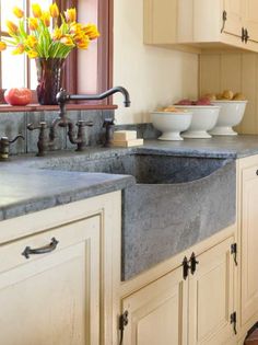 a kitchen sink sitting under a window next to a counter top with bowls on it