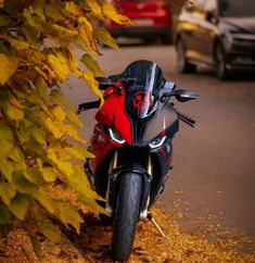 a red and black motorcycle parked on the side of a road next to some trees