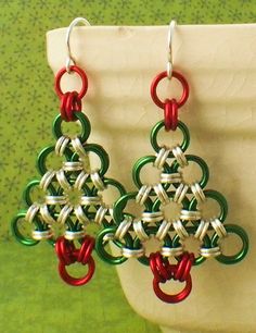 a pair of red and green earrings on top of a white vase