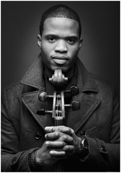 a black and white photo of a man holding a violin in his hands with both hands