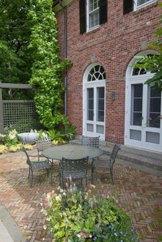 an outdoor patio with table, chairs and potted plants in front of the house