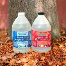 two bottles of epoxy resin sitting next to a tree