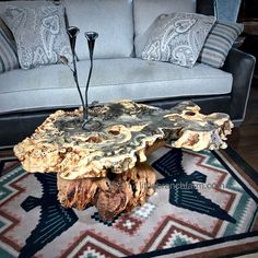 a wooden table sitting on top of a rug in front of a couch with pillows