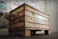 a wooden box sitting on top of a floor next to a wall