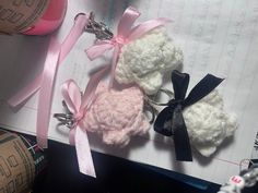 three crocheted teddy bears tied together with pink and black ribbons on top of an open notebook