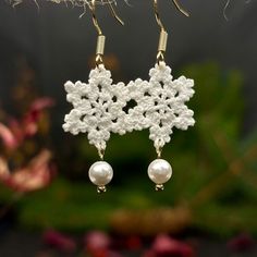 white crochet snowflake earrings with pearls hanging from gold earwires