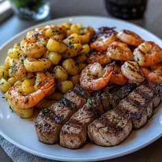 a white plate topped with steak, shrimp and potatoes