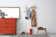 a room with a dresser, coat rack and shoes on the floor next to it