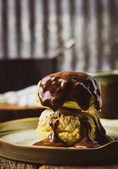 two desserts on a plate with chocolate drizzled on them and one has an egg in the middle