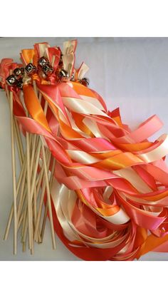 a bunch of orange and pink streamers on top of a white table with candy sticks