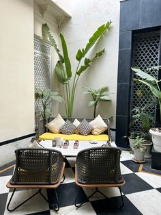 two wicker chairs sitting on top of a checkered floor next to a potted plant