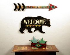 a welcome sign with an arrow and bear on it next to a wooden box that says welcome