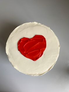 a white cake with red icing in the shape of a heart on it's side