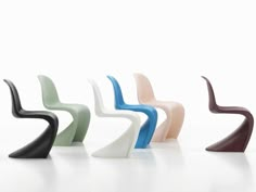 four different colored plastic chairs sitting side by side on a white surface with one chair facing the opposite direction