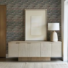 a white vase sitting on top of a wooden cabinet next to a framed picture and lamp