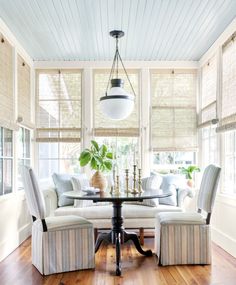 a living room filled with furniture and a round table in front of a window covered in blinds