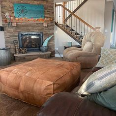 a living room filled with furniture and a fire place next to a stair case in front of a brick wall