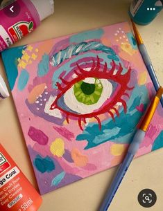 an eye is painted on a piece of paper with crayons next to it