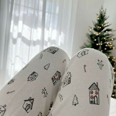 someone's feet with christmas themed socks on, in front of a christmas tree