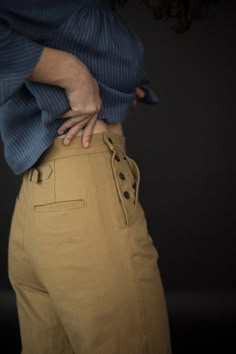 a woman with her hands on her hips wearing khaki pants and a blue shirt