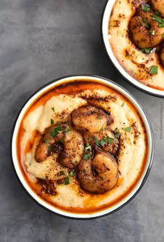 two bowls filled with food sitting on top of a table next to each other and garnished with parsley