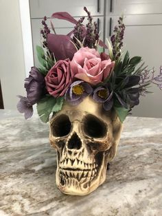 a skull with flowers in it sitting on a table