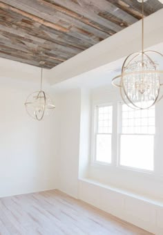 an empty room with two chandeliers hanging from the ceiling