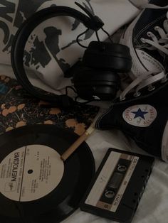 an old record, headphones, and pair of sneakers on a bed