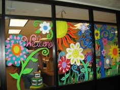 an office window decorated with colorful flowers and welcome signs on it's glass doors