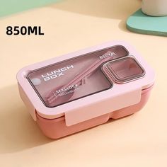 a pink lunch box sitting on top of a table next to a cup and saucer