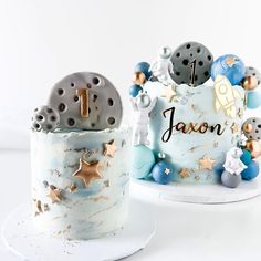 two cakes decorated with stars and planets on top of each other, one is for a baby's first birthday