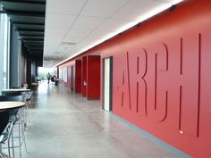 the interior of an office building with red walls and chairs on either side of it