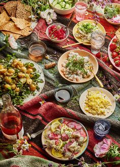 a table filled with food and drinks on top of a red cloth covered tablecloth