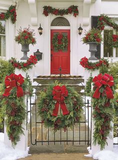 christmas wreaths on the front door of a house with red bows and poinsettis