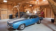 a blue car parked in a garage next to another car on the other side of the building