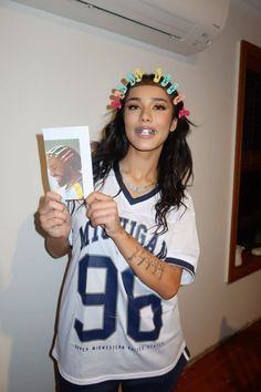 a woman with tattoos holding up a card and posing for the camera while wearing a football jersey