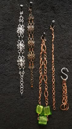 four different colored chains with bows attached to them on a black surface next to each other