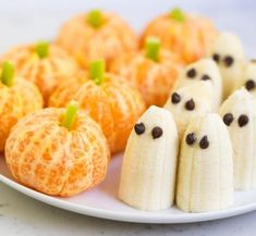 some bananas and oranges are on a plate with ghost faces painted on the side