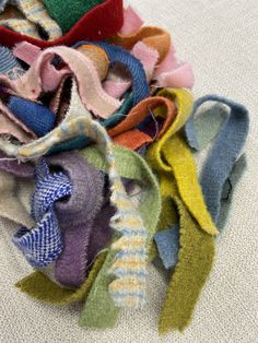 a pile of different colored pieces of fabric on the ground with one end torn off