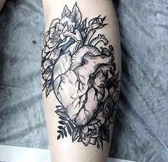 a black and white photo of a heart with flowers on the side of a person's leg