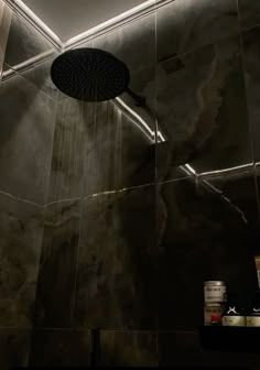 a shower head in the middle of a bathroom with dark marble walls and flooring