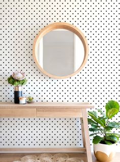 a table with a mirror and potted plant on it in front of a polka dot wall