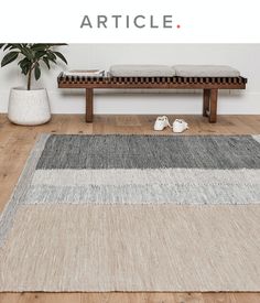 a large rug on the floor in front of a wooden bench and potted plant