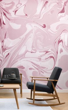 two chairs and a table in front of a wall with pink marbled paint on it