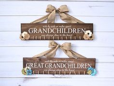 two wooden signs hanging on the side of a white wall with flowers and ribbons attached to them