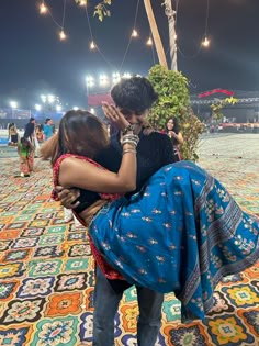 a man and woman hug in the middle of a colorful carpeted area at night