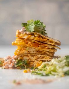 a stack of quesadillas with lettuce, corn and salsa on top