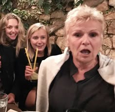 a group of women standing around each other at a table with drinks in front of them