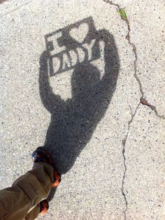 the shadow of a person holding a skateboard in front of a sign that says love dad