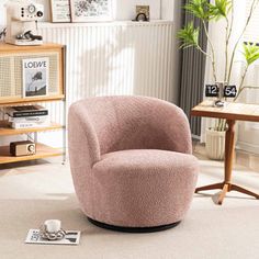 a pink chair sitting on top of a white floor next to a wooden table and bookshelf